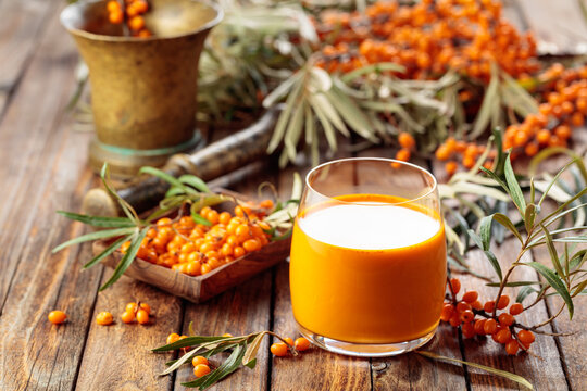 Glass of sea buckthorn juice on an old wooden table.