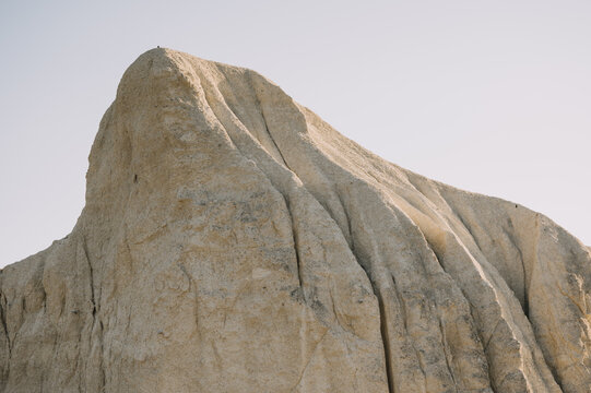 close-up view of pale sandstone cliff face showing deep vertical grooves and weathered layers in soft sunlight