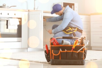 Home maintenance and plumbing repair, professional plumber fixing kitchen sink cabinet with tools...