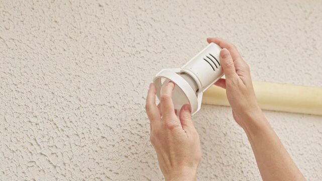 Person replaces a wall light bulb inside a white ceiling fixture