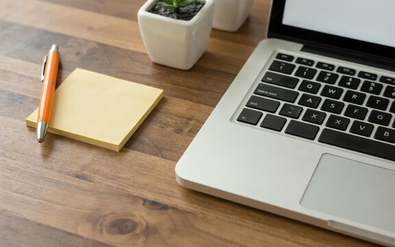 A modern laptop, pen, and sticky notes are neatly arranged with a small plant on a wooden desk. This represents modern office productivity and organized work.