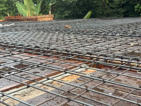 TMT steel reinforcement bars (rebar) arranged as main reinforcement for a reinforced concrete terrace slab at a residential house construction site in Kerala, India. The image shows the structural ste