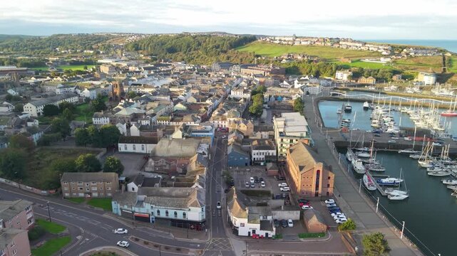 Aerial panoramic views of Whitehaven coastal town and civil parish. Town centre with architecture and main roads with moving vehicles in Sunrise, golden hour. Drone POV exploration of Devon County, UK