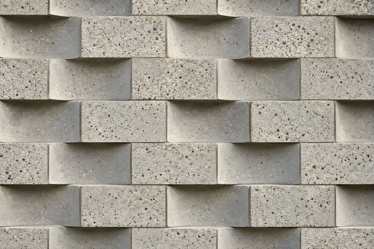 Modern concrete block wall with staggered raised elements, rough aggregate texture and geometric shadows, ideal for architecture, brutalist design and abstract backgrounds.