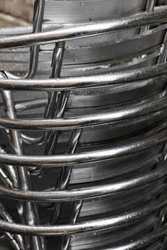 Rain Soaked Stacked Silver Metal Chairs at an Outdoor Cafe in Late Autumn. Close-up.