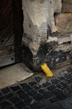 Bright Yellow Pipe Contrasting with an Old Weathered Wall, Cobblestone and Door. Close-up.