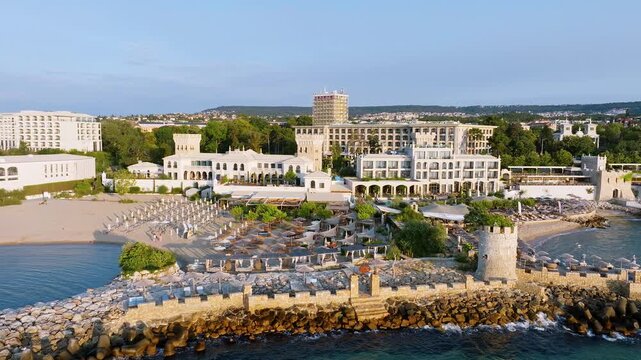 Beach umbrellas stone pier tower aerial view St Constantine and Helena resort coastline Black Sea sunrise light Varna Bulgaria travel concept horizontal video stock footage