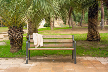 Cream fleece jacket draped over a weathered park bench outdoors.  © Katerina