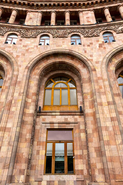 Carved pink tufa stone arches and ornate floral reliefs decorate the facade of the Armenia Marriott Hotel with wooden balconies and windows in close up detail, Yerevan, Armenia