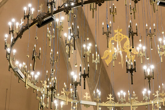 Rows of candle shaped bulbs and gilded cross ornaments hang in symmetry from the brass chandelier inside Saint Gregory the Illuminator Cathedral, Yerevan, Armenia