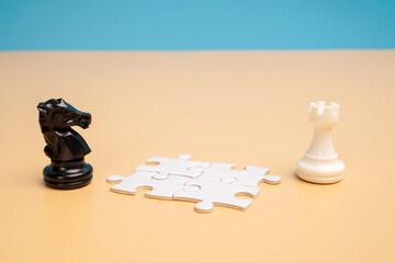 Black chess knight and white rook positioned on opposite sides of scattered white puzzle pieces. Concept of problem solving, collaboration, strategic thinking and connecting different perspectives. © Akmalism Photography