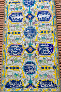 Close up detail of decorative blue and yellow ceramic tilework with floral patterns and Islamic calligraphy on a weathered brick wall of the Blue Mosque, Yerevan, Armenia