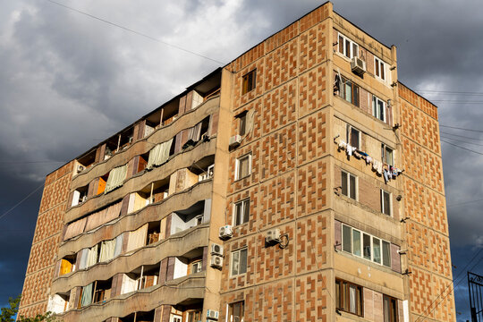 Low angle view of a towering Soviet era apartment block with laundry hanging from the balconies beneath a dramatic sky filled with heavy storm clouds, Yerevan, Armenia