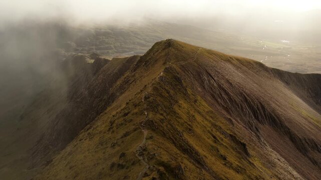 Mountain ridge path winding through clouds and sunlight