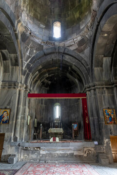 A stone altar draped with a red curtain inside Vahramashen Church is flanked by icons of the Virgin Mary beneath a vaulted stone dome and arched ceiling, Amberd, Armenia