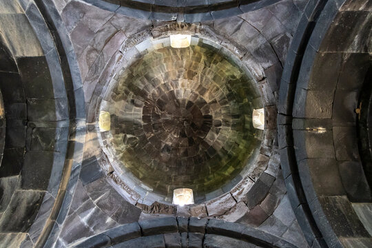 The radial stone masonry of the ceiling inside Vahramashen Church forms an intricate circular geometric pattern lit by a single narrow window above, Amberd, Armenia