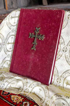 A red velvet prayer book decorated with a metal cross and gold thread embroidery rests on an embroidered cloth inside the ancient Vahramashen Church, Amberd, Armenia