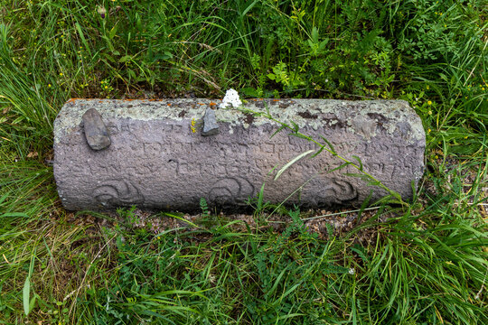 Close up of a weathered ancient Jewish gravestone lying in the grass reveals a Hebrew inscription covered in lichen and moss after centuries of weathering, Eghegis, Armenia