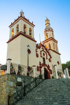 Historic Santiago Apostol church with twin bell towers and colonial architecture under a clear blue sky in Santiago, Nuevo Leon, Mexico.