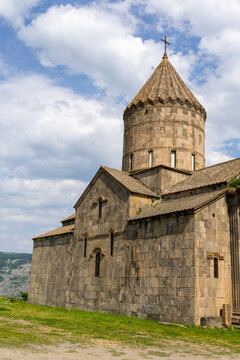 A low angle close up reveals the carved stone details ornament and arrow slit window of the ancient tower at Tatev Monastery beneath a clear blue sky, Tatev, Armenia