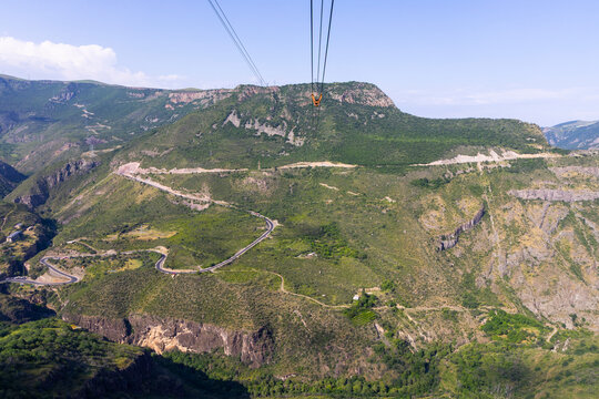 An aerial view from the Wings of Tatev aerial tramway cable car looking down over the winding mountain road through the remote forested Vorotan Gorge far below, Tatev, Armenia