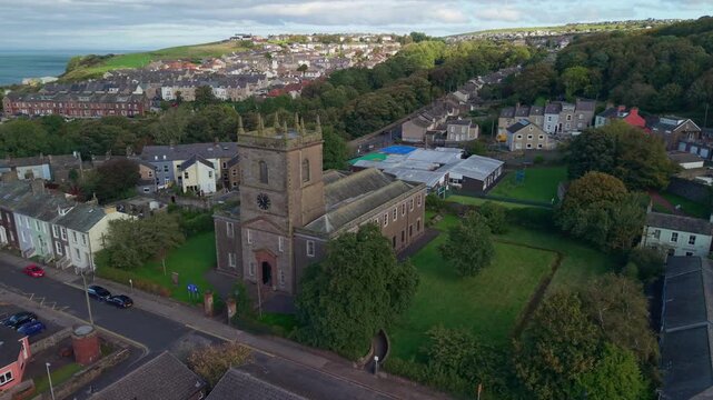 Aerial panoramic views of Whitehaven coastal town and civil parish. Demonstration of St James Church and Town centre with architecture and main roads. Drone POV exploration of Devon, England, UK