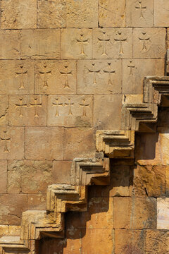 Ancient monastery wall densely covered with carved khachkar crosses and ancient Armenian script beside a narrow steep stone staircase at Astvatsatsin church, Noravank, Armenia