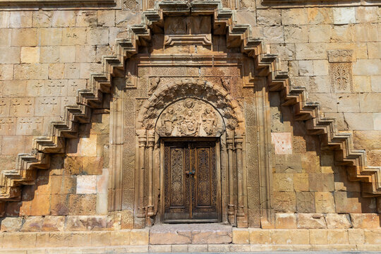 Narrow steep stone stairway climbing beside a weathered wall densely covered with carved khachkar crosses and Armenian script at Astvatsatsin church, Noravank, Armenia