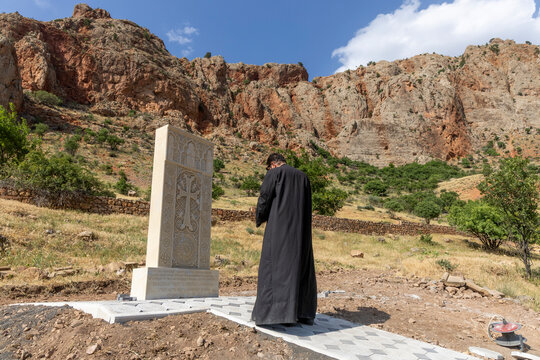 A row of carved khachkar cross stones with intricate medieval engravings stands in the grass near the Noravank monastery as weathered sandstone memorials, Noravank, Armenia