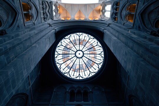 Dramatic upward view of gothic cathedral interior featuring an illuminated rose window for architectural wallpaper and background design