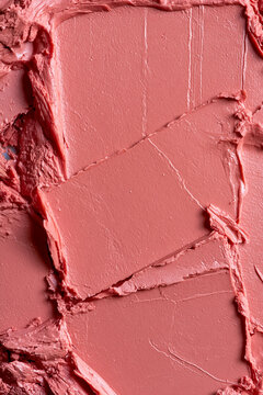 Pink peach nude cosmetic smudge background with textured creamy lipstick or blush swatch close up