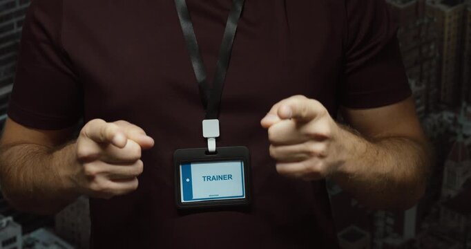 Motivated trainer showing an identification badge while raising both fists. Concept for coaching, confidence, motivation, success and professional training.