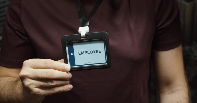 Close-up of a person displaying an employee identification badge on a lanyard. Concept for workplace access, staff identity, security and corporate employment.