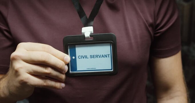 Close-up of a person displaying a civil servant identification badge on a lanyard. Concept for public service, government employment and official workplace access.