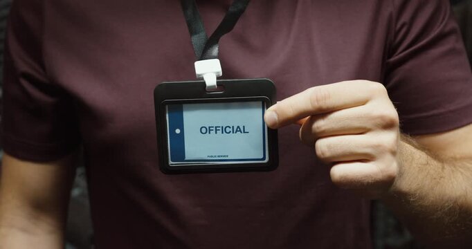 Close-up of a person displaying an official identification badge attached to a lanyard. Concept for authority, workplace access, security and verification.