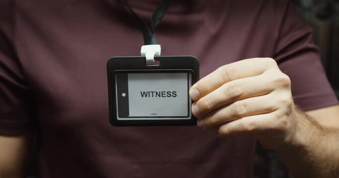 Close-up of a person displaying a witness identification badge attached to a lanyard. Concept for legal proceedings, testimony, investigation and official identification.