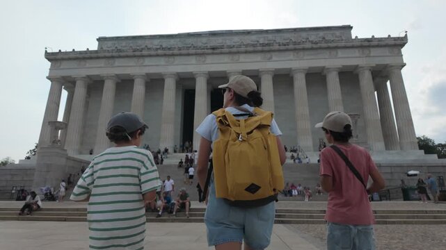 Mother with two sons walking up the steps of the lincoln memorial in washington dc, a famous monument celebrating american president abraham lincoln and national unity