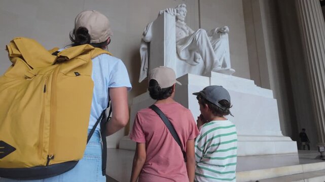 Mother and her two children observing the colossal marble statue of a seated abraham lincoln inside the lincoln memorial in washington, d.C., a national monument and a historic site