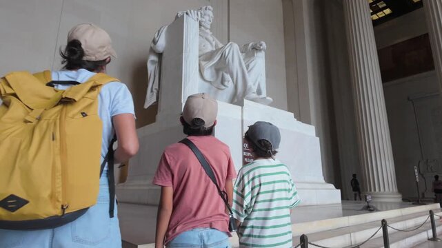 Family of tourists visiting the impressive abraham lincoln statue at the lincoln memorial in washington dc, a famous american monument and landmark for us history