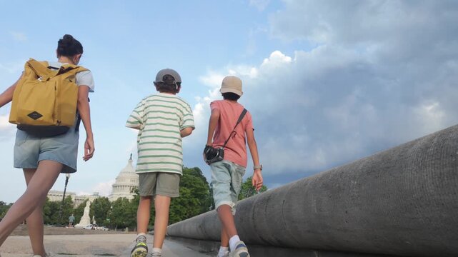 Young family of tourists with backpacks walking towards the united states capitol building in washington dc for a cultural trip and sightseeing on a cloudy summer day