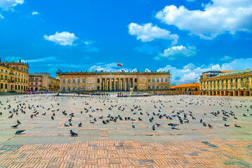 Bolivar Square in Bogota, Colombia with the National Capitol building and pigeons on the plaza under a bright blue sky. © lcrribeiro33@gmail