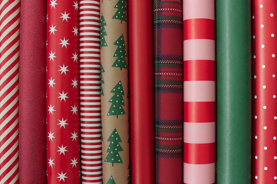Christmas gift wrapping paper collection featuring red, green, pink, white and kraft brown rolls with stripes, stars, polka dots, Christmas trees and plaid patterns. 