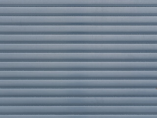 Geschlossener blauer Rollladen mit horizontalen Lamellen und feiner Rillenstruktur als Hintergrund mit Textfreiraum © Thomas Hut