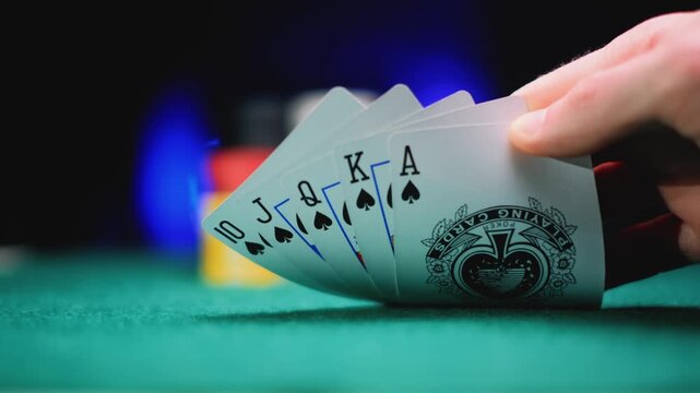 Player holding a royal flush over a green poker table. Card game, winning hand and casino night