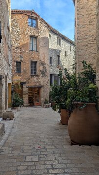 Old stone street with potted plants in Tourrettes-sur-Loup, France. 