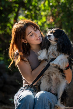 Young woman holding her dog with affection outdoors in a park