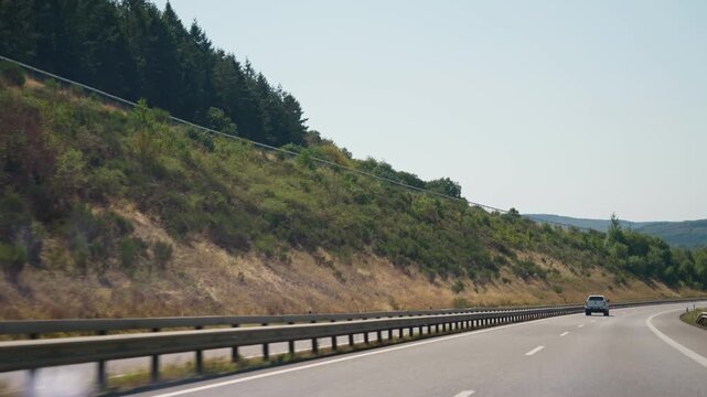 Highway traffic through forested hills a white pickup truck and a truck ahead