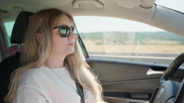 Woman driving car on sunny road trip wearing sunglasses 35 years old