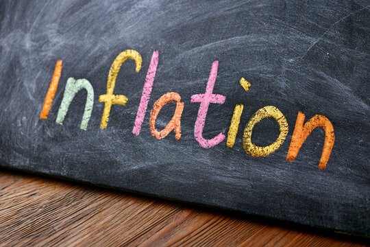Colorful chalk lettering spells inflation on a blackboard, symbolizing rising prices, economic pressure and reduced purchasing power.