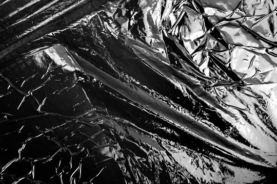 Macro close up of shiny black wrinkled plastic wrapper surface texture